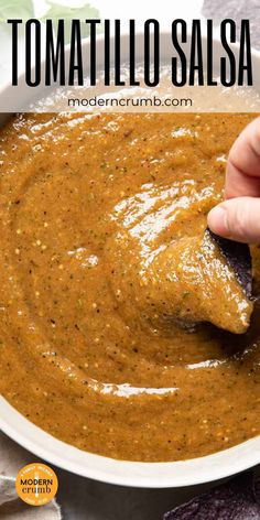 a hand dipping tortillo salsa into a white bowl