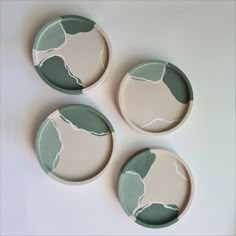 three green and white plates sitting on top of a table next to each other with leaves painted on them