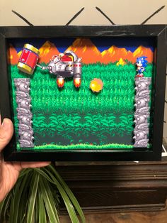 a hand holding up a video game frame with an image of a robot on it