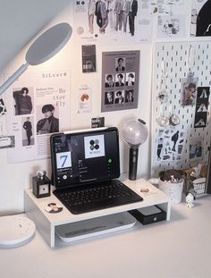 a laptop computer sitting on top of a white desk next to a lamp and other items