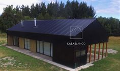 a black building with a basketball hoop on the top of it's roof in front of some trees