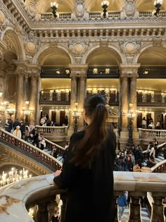 a woman standing in front of a staircase filled with people