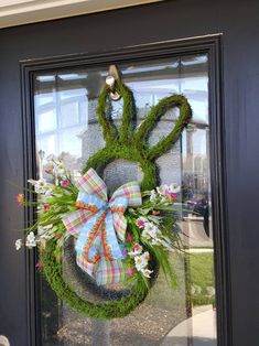 a wreath with an animal's head made out of moss and flowers is hanging on the front door