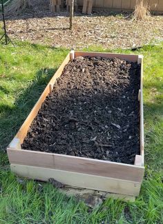 a wooden box filled with dirt in the grass