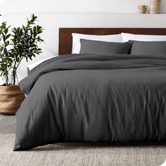 the bed is made with dark gray linens and pillows, along with a potted plant