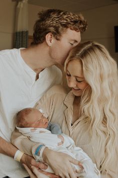 a man and woman holding a baby in their arms