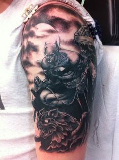 a man's arm with a black and grey tattoo on it, including an image of a demon