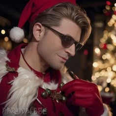 a man dressed up as santa clause in front of a christmas tree wearing sunglasses and holding a pen