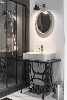 a black and white bathroom with a sink, mirror and shower stall in the corner