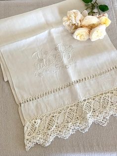 two white roses are sitting on top of the table cloths that have been embroidered onto them