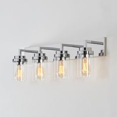 four light bathroom fixture with clear glass shades and chrome finish, on white wall background