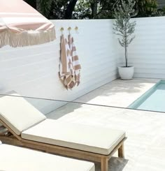 two lounge chairs sitting in front of a pool with towels hanging on the wall behind them