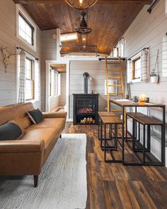 a living room filled with furniture and a fire place next to a wooden floored wall