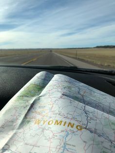 a map sitting on the dashboard of a car in front of a road and sky