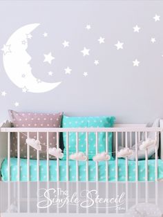 a baby crib in front of a wall with stars and moon decals