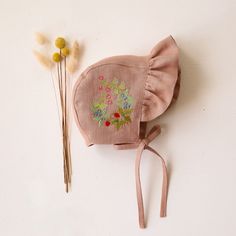 a pink hat with flowers on it next to a pair of sticks and a flower headband