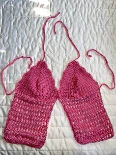 two pink crocheted handbags are laying on a white bed sheet and one has a string attached to it