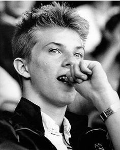 black and white photograph of a young man with his hand on his mouth looking up