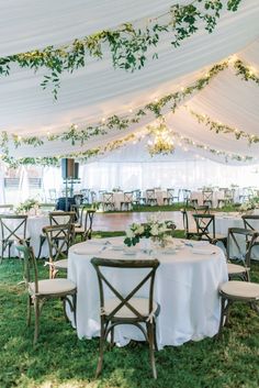 an outdoor tent with tables and chairs set up for a wedding reception in the grass