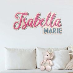 there is a stuffed animal on the couch in front of the name wall decal