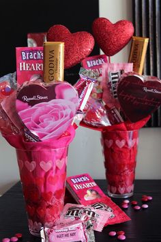 two vases filled with candy and heart shaped candies on top of a table