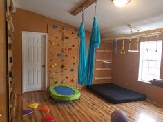 a child's playroom with climbing wall, gym equipment and other toys on the floor