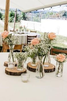 flowers are in vases on wooden slices at a wedding reception under an awning