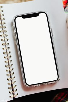 an iphone sitting on top of a notebook next to a pen