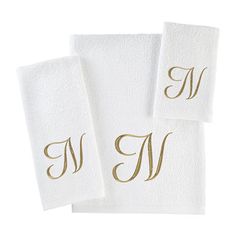 three white towels with gold monogrammed initials