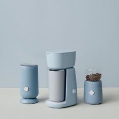 three different types of coffee makers sitting on a white table with blue walls in the background