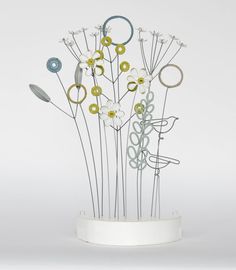 a white vase filled with lots of different types of metal flowers and circles on top of each other