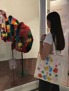 a woman carrying a shopping bag in front of some art