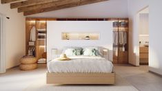 a bedroom with a bed, closet and wooden beams on the ceiling is lit by sunlight