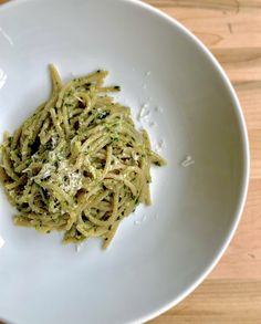 a white plate topped with pasta covered in pesto