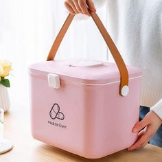 a woman holding a pink cooler bag on top of a wooden table