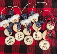 four snowman ornaments are sitting on a red and black checkered tablecloth