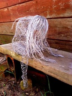 a wire sculpture sitting on top of a wooden bench