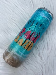 a blue and gold glittered tumbler sitting on top of a white fur covered floor