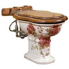 an old fashioned toilet with flowers painted on the side and wooden seat cover over it