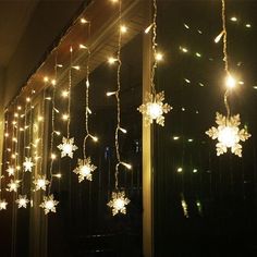 snowflakes are hanging from the ceiling in front of a window with lights on it