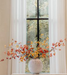 a vase filled with flowers sitting on top of a white table next to a window