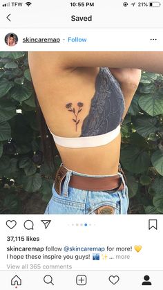 a woman with a tattoo on her back is standing in front of some leaves and flowers