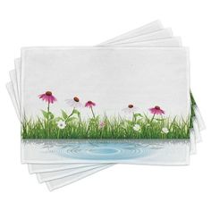 four napkins with pink flowers and green grass in the water on top of them