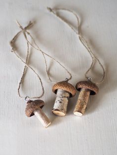 three necklaces made out of cork with mushrooms hanging from the sides on a white surface