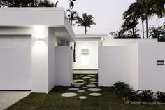 a white house with a pathway leading to the front door and entry way that leads into the back yard