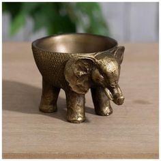 an elephant shaped bowl sitting on top of a wooden table next to a potted plant