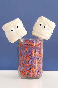 two marshmallows with eyes and sprinkles in a jar