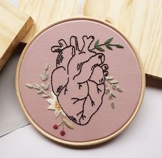 an embroidered heart on a pink background with flowers and leaves in the hoop next to wooden blocks