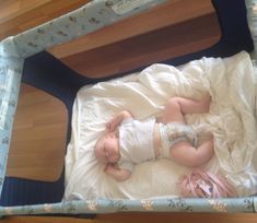 a baby laying in a crib on top of a wooden floor