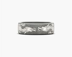 a black and white ring with two dragon designs on the inside, in front of a gray background